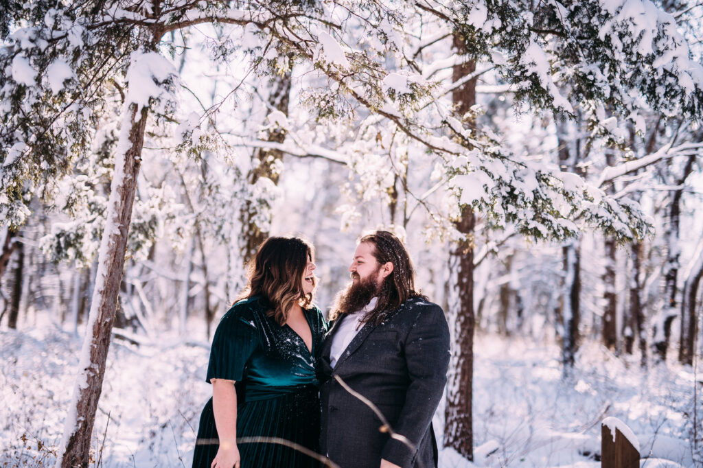 winter engagement photo inspiration of a cute couple laughing in a beautiful forest covered with snow