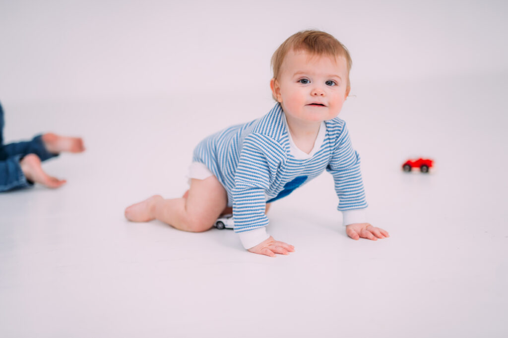 cute little boy in a blue birthday onesie in a white studio